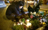 Une femme allume une bougie près du restaurant "Le Petit Cambodge" à Paris, le 31 décembre 2015