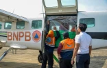Des agents de l'Agence nationale de gestion des catastrophes chargent du chlorure de sodium dans un avion avant une opération d'ensemencement des nuages à Palangkaraya, dans le Kalimantan central, le 2 août 2026 en Indonésie