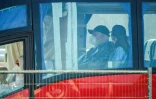 Un passager porte une combinaison de protection et un masque à bord d'un autobus après avoir été évacué du navire de croisière touché par un foyer d'hantavirus, le 10 mai 2026 à Granadilla de Abona, sur l'île espagnole de Tenerife 