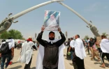 Un partisan du leader irakien Moqtada Sadr arbore son portrait sous une structure de sabres à Bagdad avant une prière collective, le 5 août 2022
