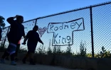 Des passants marchent devant une grille sur laquelle est inscrit le nom de Rodney King, victime de violence policière, à Los Angeles (Californie) le 9 juin 2020