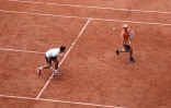 Le Serbe Novak Djokovic (G), N.1 mondial, joue avec un ramasseur de balle pendant une séance d'entraînement sur le Court Philippe-Chatrier à la veille de l'ouverture du tournoi de Roland Garros, le samedi 21 mai 2022 à Paris