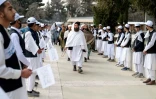 Des élèves tiennent le drapeau taliban, alignés pour accueillir les autorités locales, lors d'une cérémonie pour la rentrée scolaire, à l'école Amani de Kaboul, le 20 mars 2024 en Afghanistan