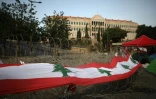 Un large drapeau libanais placé sur les barbelés devant le siège du gouvernement à Beyrouth, le 26 octobre 2019