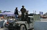 Des membres de l'unité "Badri 313", une composante des forces spéciales talibanes, dans des véhicules blindés Humvee devant l'entrée principale de l'aéroport de Kaboul, le 28 août 2021