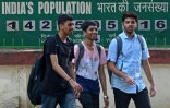 Des jeunes passent devant l'horloge démographique de l'Inde installée sur la facade de l'Institut international des sciences de la population, le 27 avril 2023 à Bombay