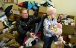 La déplacée ukrainienne Iana et sa fille Maïa au milieu des cartons de vêtements d'un centre d'aide à Lviv, le 11 avril 2022