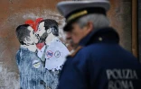 Un policier devant une peinture murale de l'artiste TVBOY représentant les leaders du MOUvement 5 EToiles Luigi de Maio et de la Ligue Matteo Salvini, le 23 mars 2018