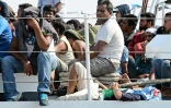 Des migrants attendent d'être débarqués d'un bateau des guardes-côtes italiens à leur arrivée le 7 août 2015 à Pozzalo en Italie