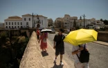 Des touristes se protègent du soleil avec des parapluies le 9 août 2024 à Ronda, en Espagne, touché par une vague de chaleur