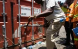 Un membre de l'unité de lutte contre la criminalité organisée transnationale ouvre l’un des quatre conteneurs saisis contenant des comprimés et des gélules de tapentadol en provenance d’Inde, au terminal de Freetown, le 27 mars 2026 en Sierra Leone 