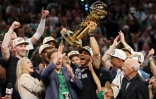 L'entraîneur principal des Boston Celtics, Joe Mazzulla, crie en soulevant le trophée après la victoire 106-88 de son équipe contre les Mavericks de Dallas lors du match 5 de la finale NBA 2024 au TD Garden à Boston, le 17 juin 2024
