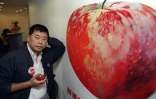 Le magnat de la presse et fondateur d'Apple Daily, Jimmy Lai, posant devant une affiche de pomme, à Hong Kong, le 14 juin 1995