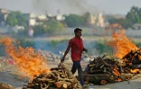 Un homme marche entre les bûchers d'un crématorium à Allahabad, en Inde, le 27 avril 2021