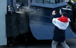 Un manifestant face aux policiers anti-émeute pendant une manifestation à Minsk, le 25 octobre 2020