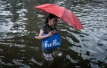 Une femme se fraye un chemin dans une rue inondée de Bangkok, où l'état de catastrophe naturelle a été déclaré après des pluies diluviennes qui ont inondé habitations, commerces et axes de circulation, le 27 septembre 2026