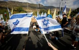 Drapeaux israéliens arborés lors d'une manifestation près de Kiryat Shmona, dans le nord d'Israël, pour exiger du gouvernement un accord garantissant la libération des otages retenus à Gaza, le 17 août 2025