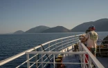 Des touristes sur le pont d'un ferry, le 3 août 2026, en route vers l'île grecque d'Ithaque, patrie d'Ulysse, héros de la mythologie grecque.
