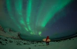 Un surfeur observe une aurore boréale à Unstad dans les îles norvégiennes Lofoten, le 10 mars 2016