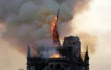 Le clocher et la flèche de la cathédrale Notre-Dame s'effondrent alors que l'édifice est en proie aux flammes dans le centre de Paris, le 15 avril 2019