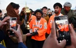 Le cavalier Sarwar Pahlawan (c) de l'équipe Yama Petroleum porte le trophée après avoir remporté la finale du tournoi de bouzkachi, le 8 mars 2024 à Mazar-i-Sharif, en Afghanistan