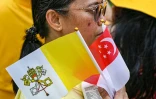 Des fidèles catholiques portant les drapeaux de Singapour et du Vatican attendent l'arrivée du pape François à Changi Jurassic Mile à Singapour, le 11 septembre 2024