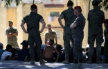 Un jeune migrant regarde un militaire espagnol, avant d'être escorté avec d'autres migrants vers le Maroc, le 2 août 2026 dans l'enclave espagnole de Ceuta