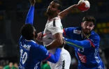 L'arrière gauche algérien Messaoud Berkous tire au but malgré la défense des Français, l'arrière droit Dika Mem et le pivot Ludovic Fabregas, lors de leur match du Mondial de handball, le 20 janvier 2021 dans la Ville du 6 Octobre, un faubourg proche du Caire