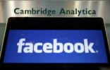 Le logo de Facebook affiché sur un ordinateur portable devant la plaque d'entrée de la société britannique Cambridge Analytica à Londres, le 21 mars 2018