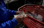 Un "canner" reçoit quelques billets de dollars en échanges des cannettes et bouteilles qu'il a ramenées dans un centre de recyclage, au prix de 5 cents par article recyclé