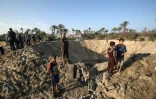 Des enfants palestiniens marchent autour d'un cratère creusé par une frappe israélienne, dans le sud de la bande de Gaza, le 2 novembre 2019