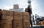 Un membre de l'unité de lutte contre la criminalité organisée transnationale charge des cartons contenant du tapentadol saisis dans des conteneurs en provenance d’Inde, au terminal de Freetown, le 27 mars 2026 en Sierra Leone 