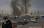 Une femme se couvre le visage pour se protéger de la fumée après une attaque de missile russe à Kiev, le 6 avril 2025 en Ukraine