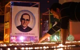 Un fidèle allume une bougie devant un portrait de l'archevêque Oscar Romero, à Ciudad Barrios, sa ville natale, au jour de sa canonisation le 14 octobre 2018