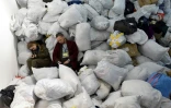 Des bénévoles d'un centre d'aide humanitaires se reposent au milieu de sacs de vêtements pour les réfugiés, à Lviv (Ukraine), le 19 mars 2022
