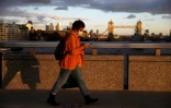 Un passant traverse le London Bridge au coucher du soleil à Londres le 3 novembre 2020
