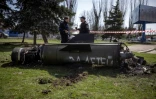 Des policiers ukrainiens devant les débris d'un missile sur lequel est écrit en russe "pour nos enfants" près de la gare de Kramatorsk, cible d'un bombardement meurtrier, le 8 avril 2022 dans la région du Donbass, dans l'est de l'Ukraine