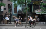 Des habitants en terrasse devant un bar à New York le 7 juin 2020