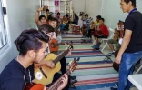 Des réfugiés et des migrants suivent un cours de guitare dans le camps de Moria, sur l'île de Lesbos, le 25 septembre 2018