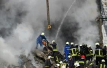 Des pompiers recherchent des survivants dans les décombres d'un immmeuble touché par une frappe russe, le 28 avril 2023 à Ouman, en Ukraine