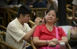  Un nettoyeur d'oreilles en plein activité sur une cliente, dans la célèbre maison de thé de Chengdu, le 8 septembre 2016