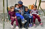 Djamoliddine Makhmaliev, déplacé climatique, avec ses petits-enfants, dans sa nouvelle maison du district de Khourosson, le 26 mars 2024 au Tadjikistan