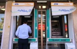 Un homme retire de l'argent à un distributeur automatique de la banque Tejarat, dans une rue à Téhéran, le 25 mai 2026 en Iran