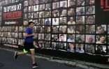 Un coureur passe devant un panneau montrant les portraits des otages israéliens dans la bande de Gaza, le 15 janvier 2025 à Jérusalem