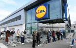 Des personnes portant des masques de protection attedent devant l'entrée d'un supermarché Lidl, le 23 février 2020 à Casalpusterlengo, en Italie