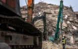 Un secouriste passe devant des pelleteuses utilisées pour trouver des personnes piégées dans les décombres sur le site de l'effondrement d'un immeuble en construction à Bangkok, le 1er avril 2025