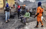 Des partisans de l'opposition au pouvoir kényan devant une voiture calcinée à Nairobi, le 19 juillet 2023