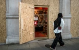 Une touriste passe devant un magasin de souvenir protégé par des panneaux de contreplaqué, le 12 juin 2026 à Genève, en Suisse, avant les manifestations anti-G7 en marge du sommet à Evian