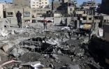 Des Palestiniens inspectent les destructions après une frappe israélienne qui a touché une école transformée en abri pour déplacés dans la ville de Gaza, le 13 avril 2025