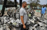 Des Algériens devant un manège brûlé par les incendies qui font rage dans la ville algérienne d'el-Kala, le 17 août 2022